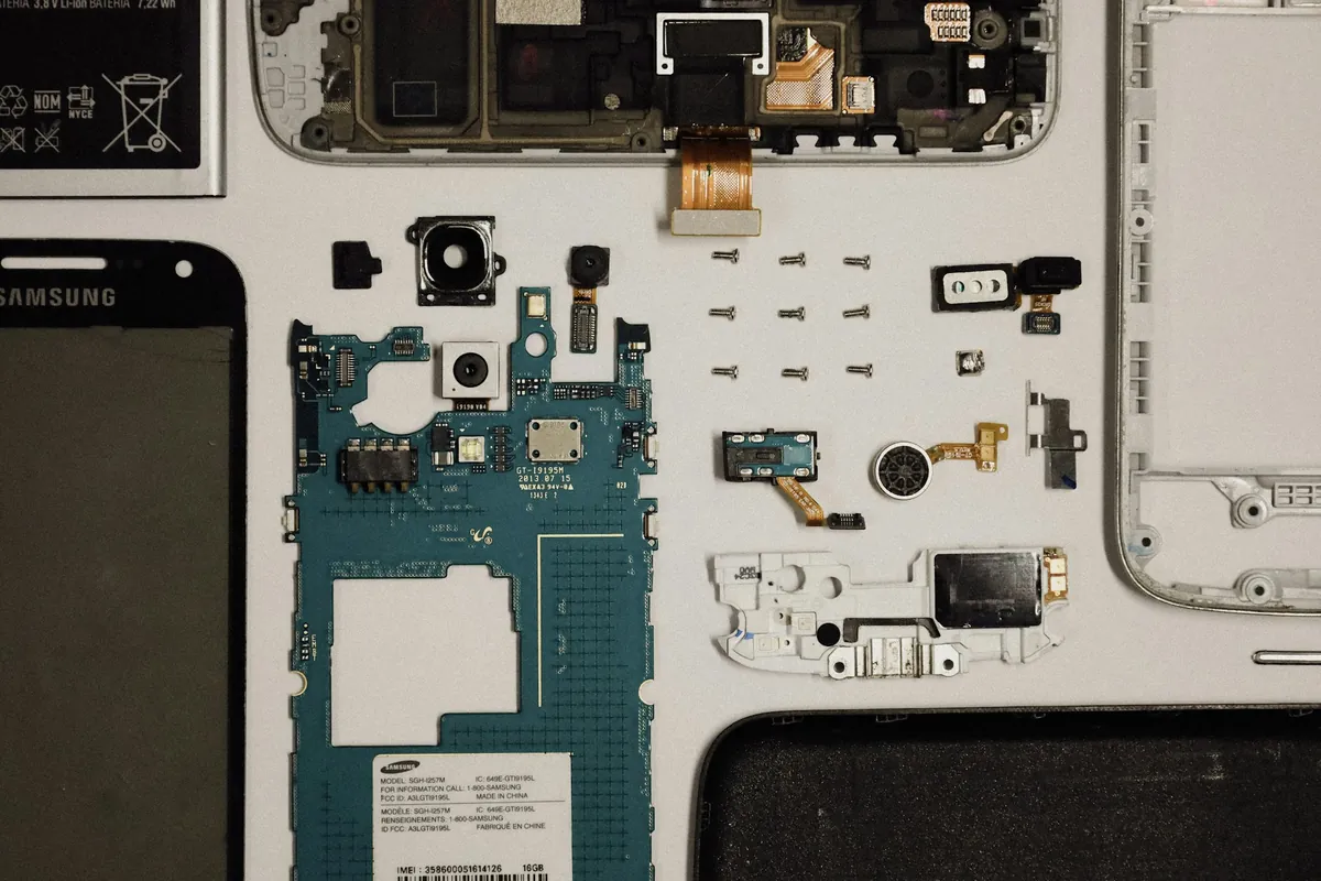 Smartphone Samsung Galaxy démonté, carte mère et composants posés sur l'établi